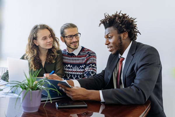 Two clients and loan officer reviewing terms for international business loans.